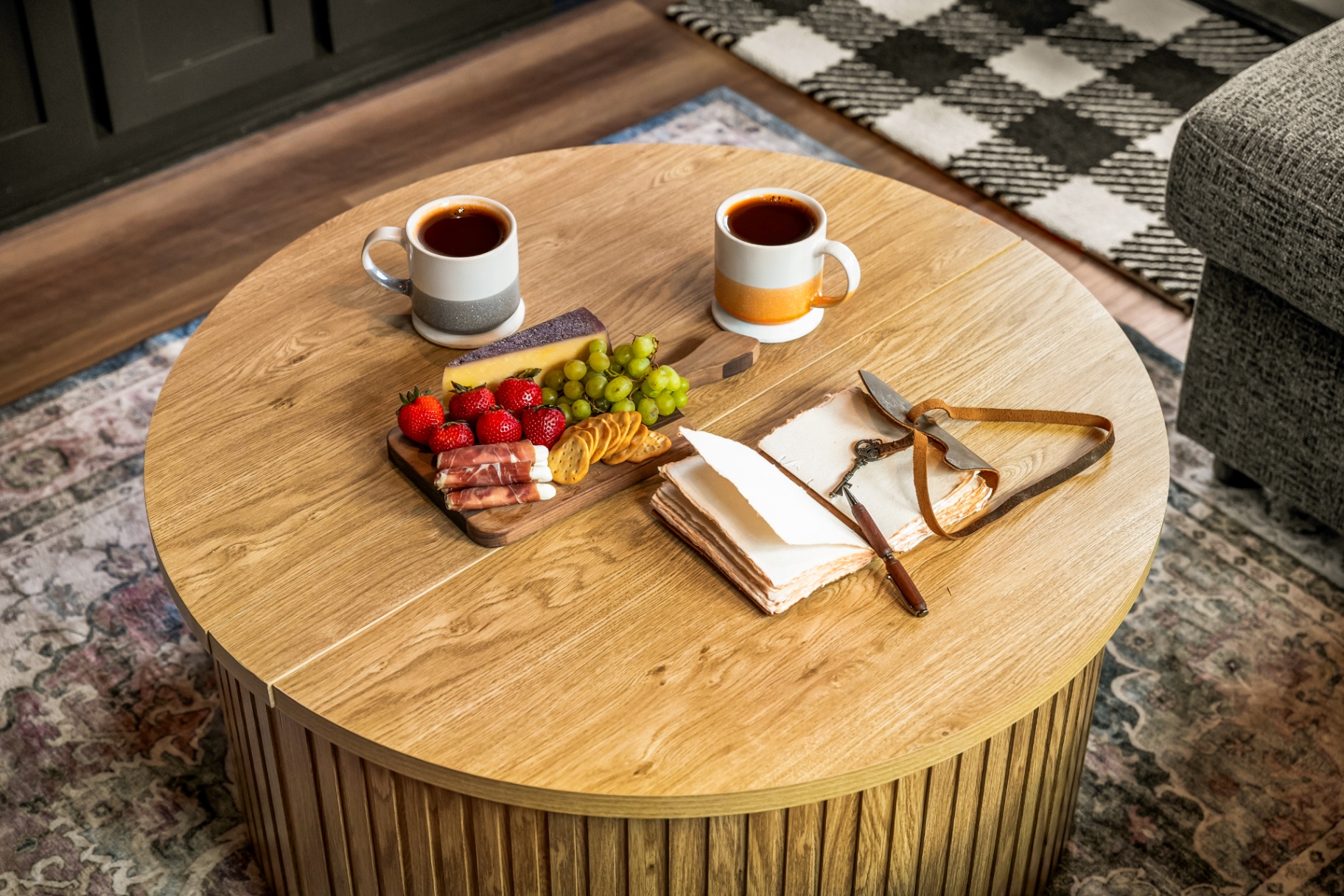 Wooden coffee table with mugs, fruit, and cheese