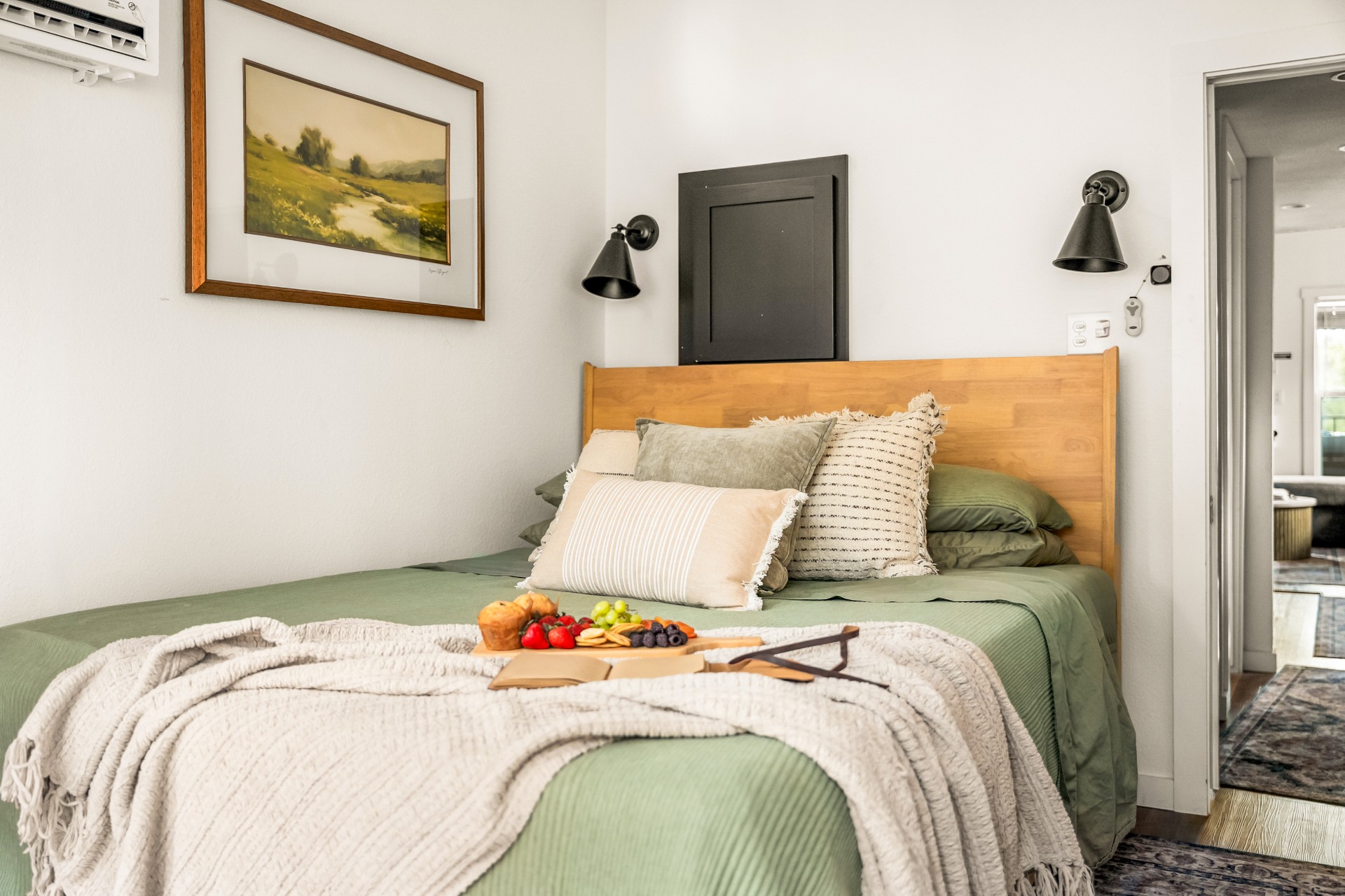 Bedroom with sage linens and framed landscape art
