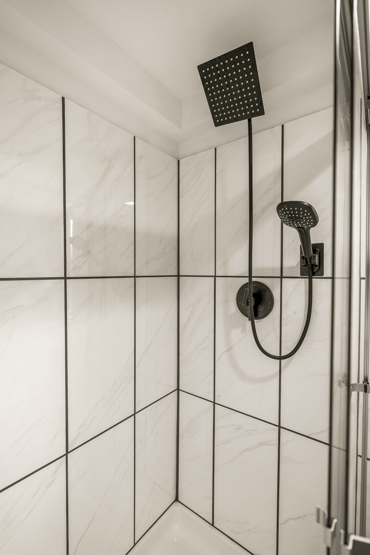 White marble-tiled shower with matte black rainfall fixture