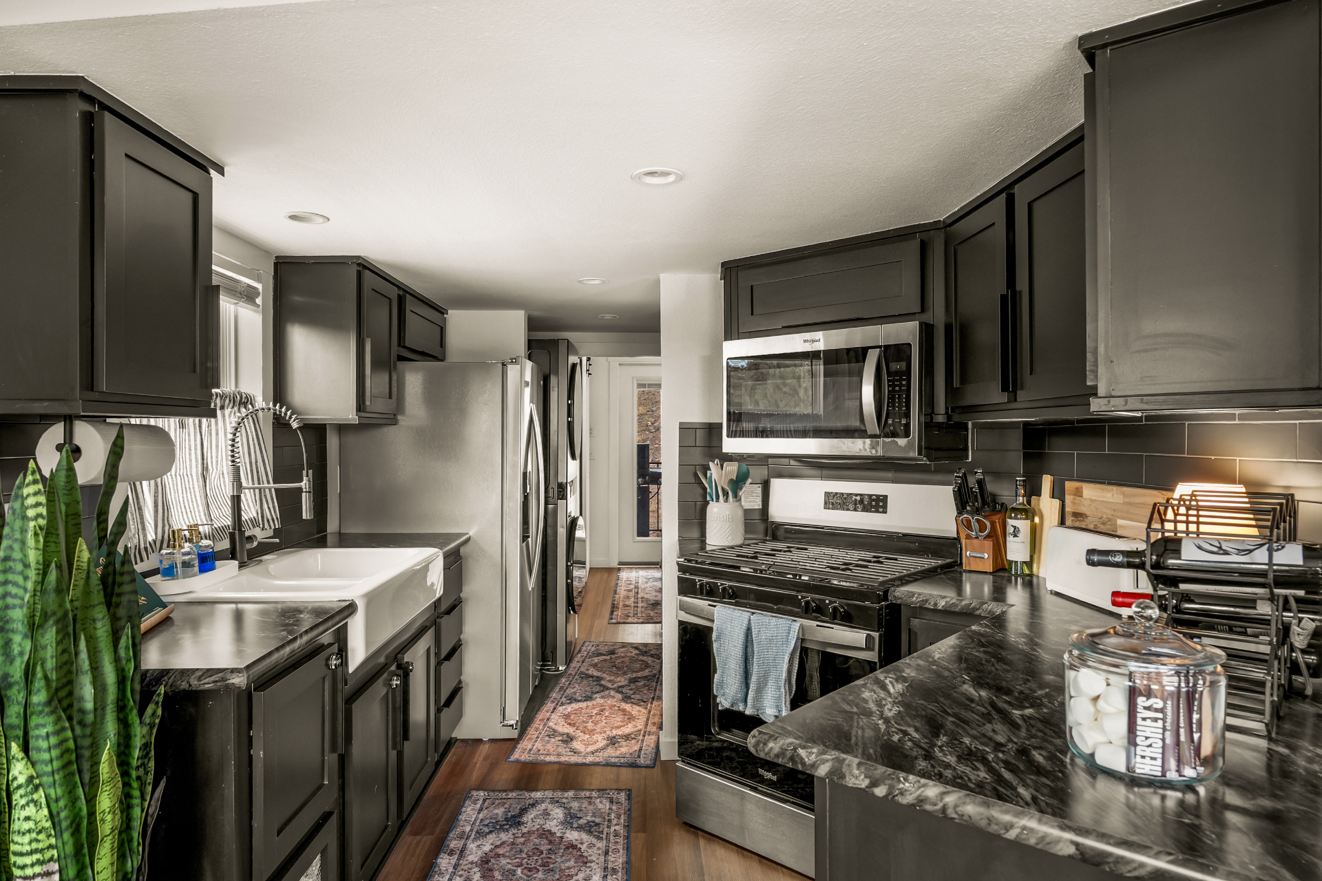 Full kitchen with gas range, farmhouse sink, and dark cabinetry