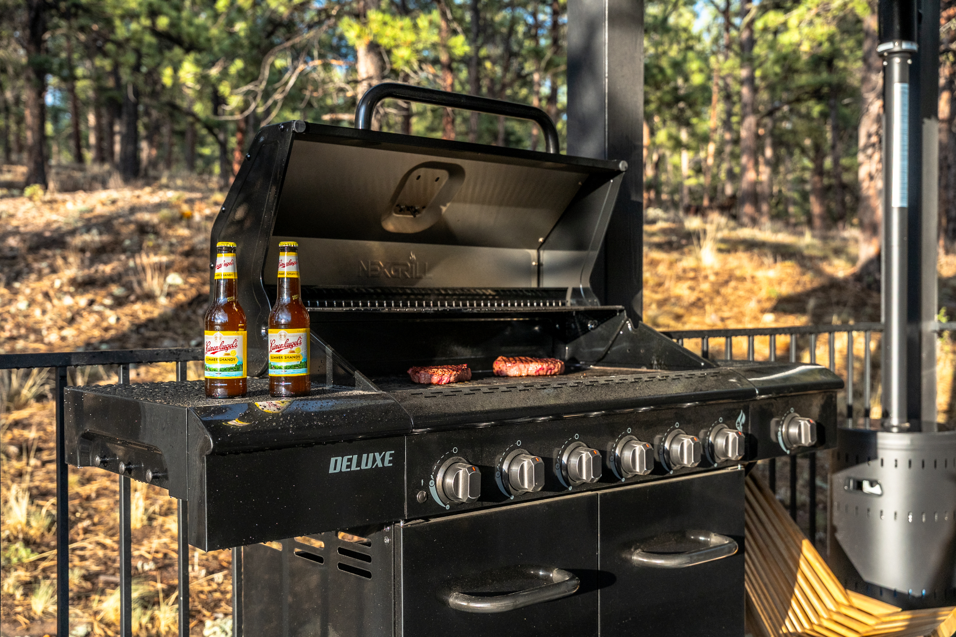 Gas grill on the deck with cold drinks and forest backdrop