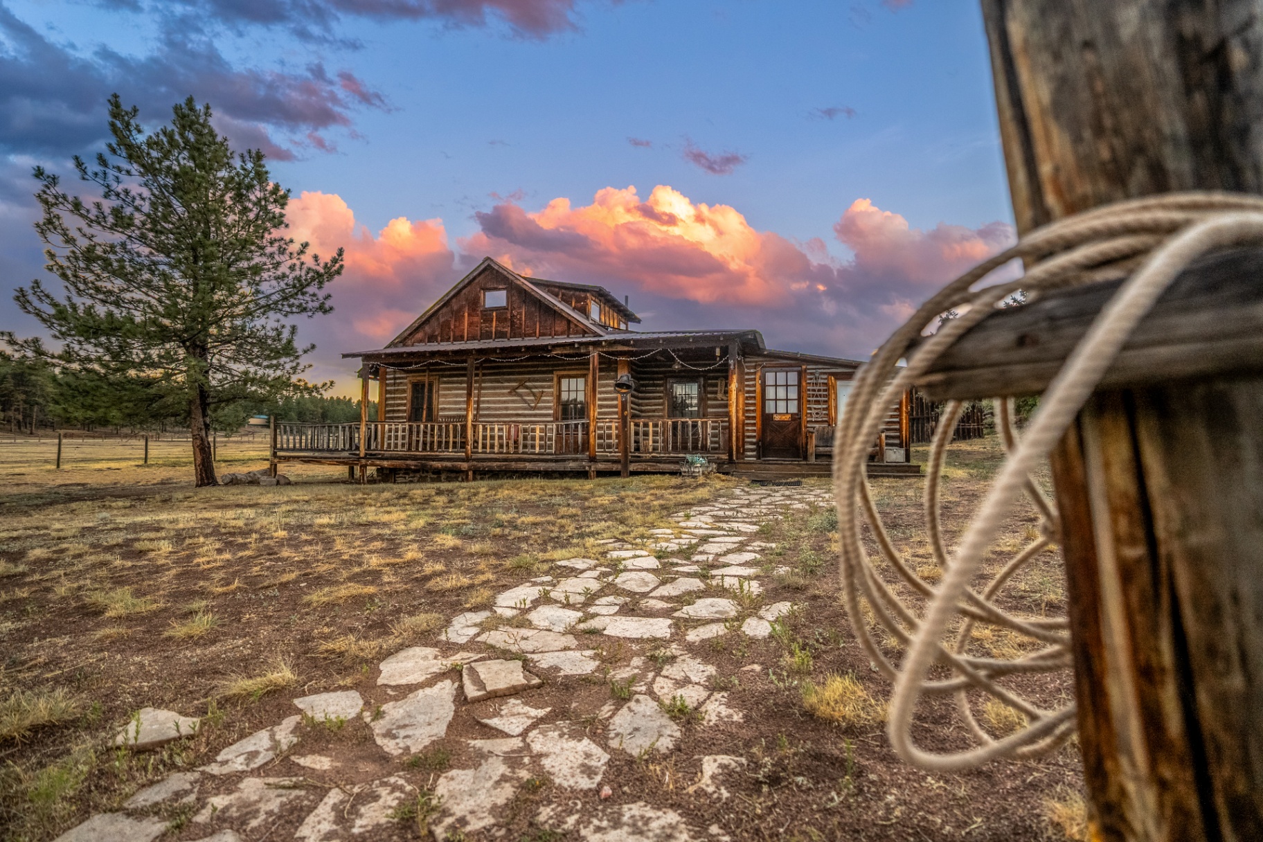 Historic log cabin at M Lazy C Ranch under a pink sunset sky
